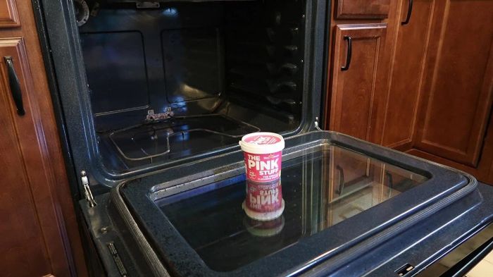 A photo showing The Pink Stuff placed in front of a dirty oven, ready for action.