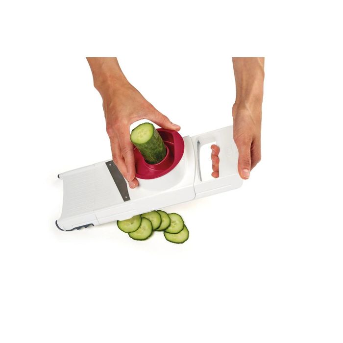 A person using a slicing blade to cut a cucumber