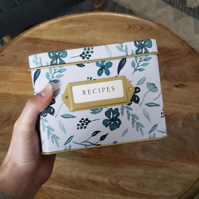 A reviewer holding the floral recipe box featuring a white and blue design in their hands.