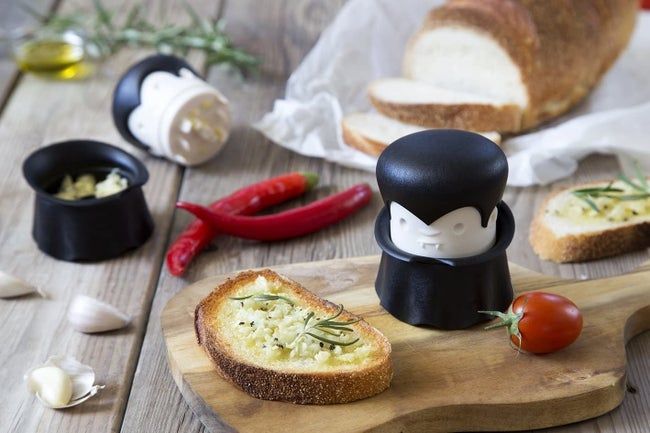 The garlic mincer shaped like Dracula (just twist the head to crush) beside some garlic bread