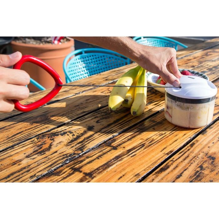 A person pulling the cord of a food processor to puree ingredients.