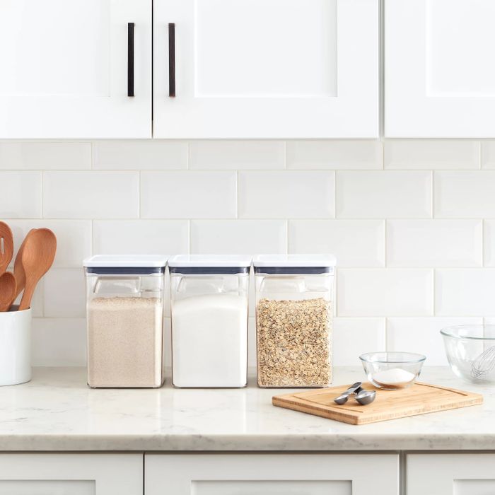 The storage containers holding sugar, flour, and oats on a kitchen counter.