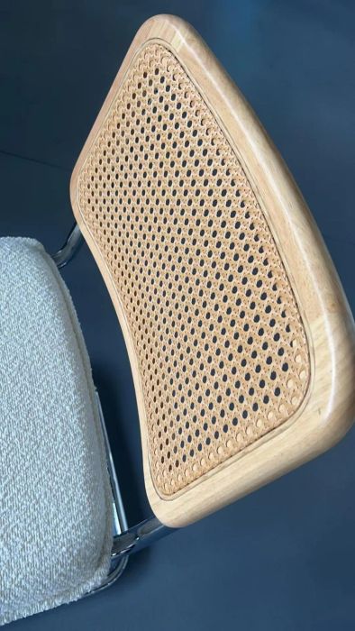 A close-up view of a chair showcasing its wicker backrest and plush seat, emphasizing the contrast of its materials and textures.