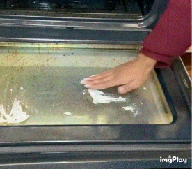 A gif showing someone applying the cleaner to a dirty oven door and wiping away the stains