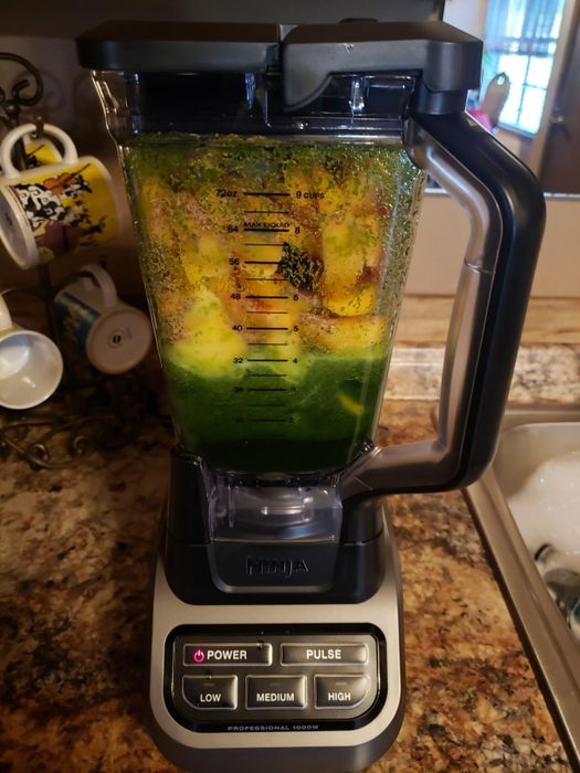 The blender filled with a mix of fruits and greens