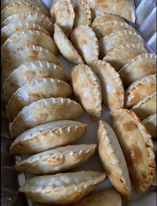 A row of golden, perfectly shaped empanadas