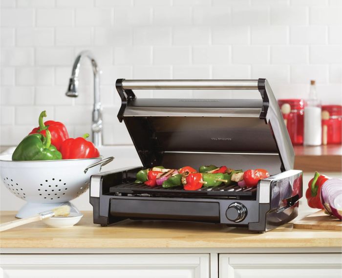 An indoor grill grilling skewers in a kitchen setting