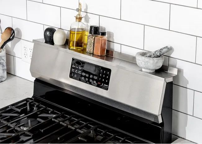 A stove with the shelf installed across the top, holding spices.
