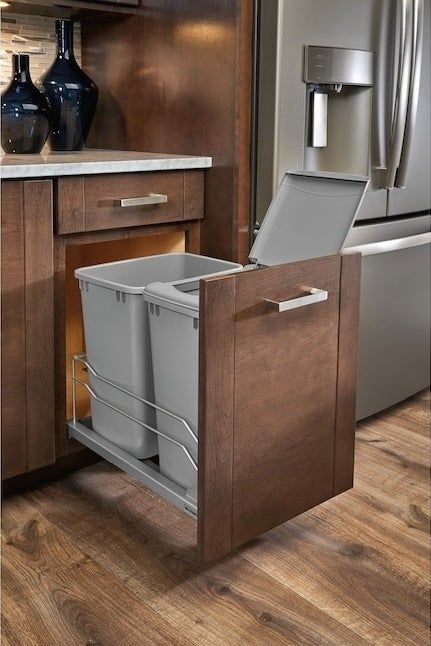 A kitchen cabinet with a pull-out trash and recycling bin system, designed for easy waste separation and convenience