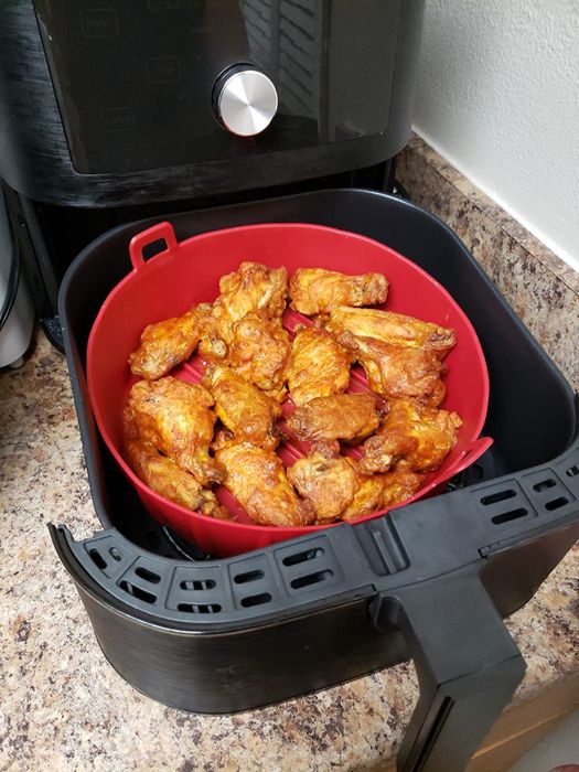 The red silicone basket placed inside an air fryer