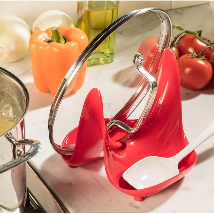 A lid and spoon rest placed on a kitchen counter, holding a lid and spoon.