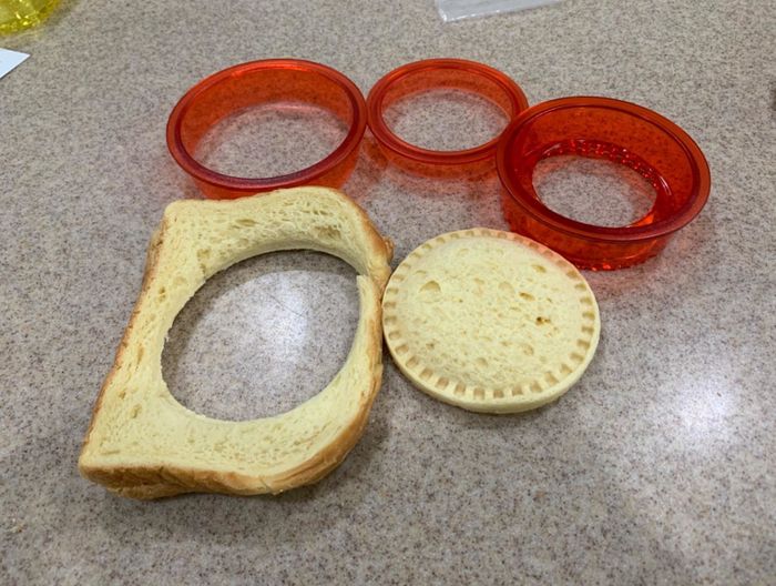 Reviewer’s photo of the sandwich cutters placed next to a slice of bread with a perfectly round crustless shape removed