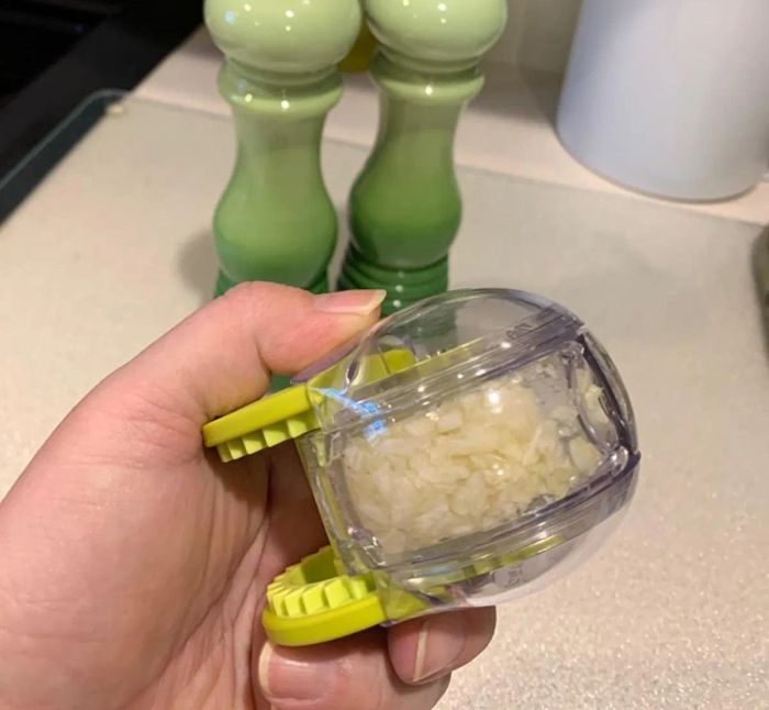 A reviewer holding the garlic chopper filled with freshly chopped garlic.