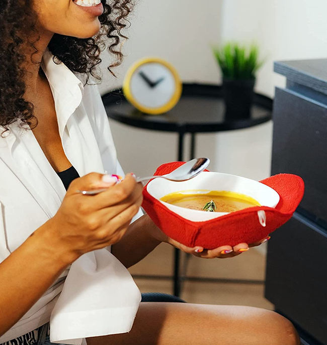 A model holding a bowl of soup in a red cloth holder