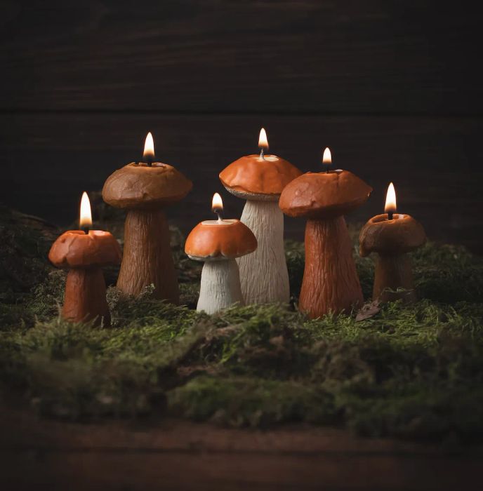 Mushroom-shaped candles arranged on moss, glowing softly to create a cozy, woodland-inspired atmosphere