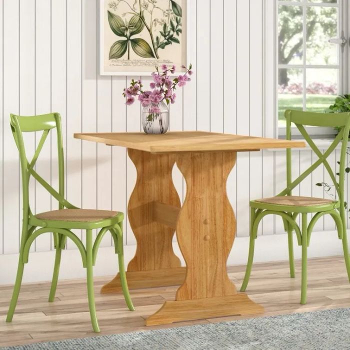 A wooden table with flowing, wavy legs, paired with two green chairs on either side