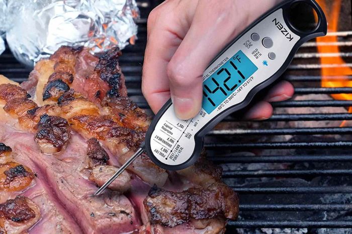 a reviewer using the thermometer to check the temperature of a piece of meat on the grill