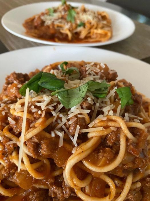 a reviewer’s photo featuring two plates of homemade spaghetti topped with a tomato meat sauce