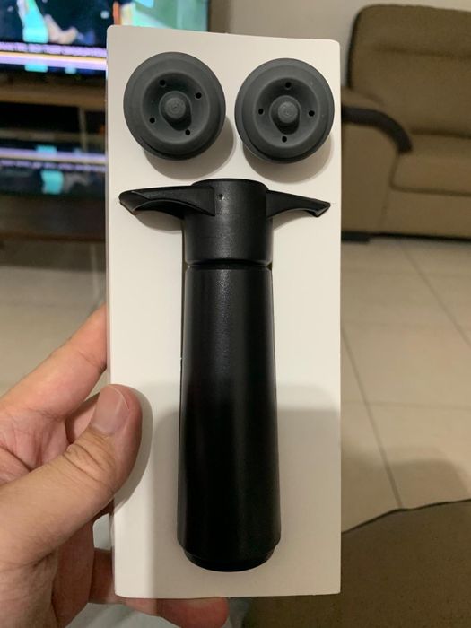 A reviewer demonstrating the wine saver pump with two included wine stoppers