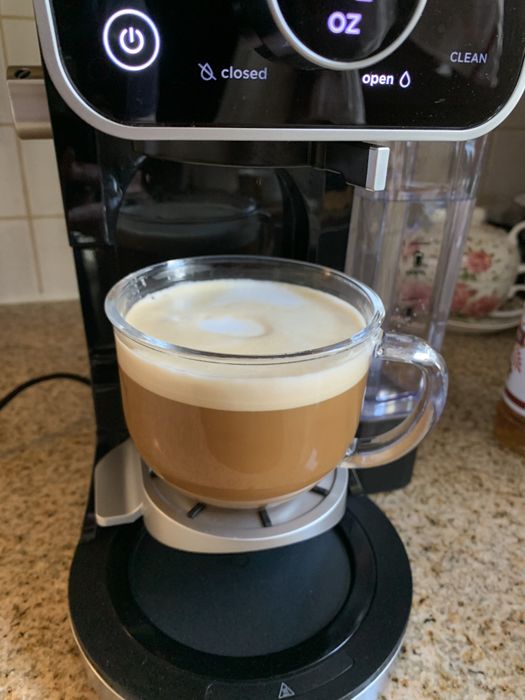 A cup of coffee with frothy milk placed beneath the Ninja DualBrew Pro