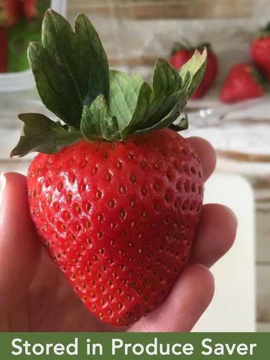 A hand holding a perfectly fresh strawberry with text that reads