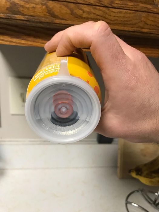 The cover securely placed over the opening of a can tilted on its side, demonstrating that the cover is leakproof