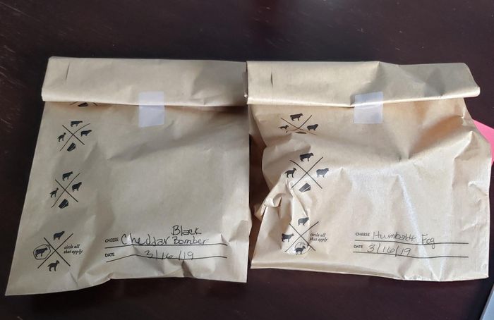 A reviewer’s photo showing two labeled storage bags, each with a date and the type of cheese inside