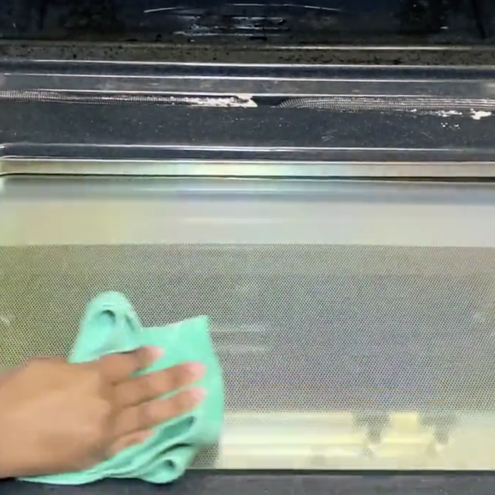 A model wiping the Oven Scrub from a clean oven door