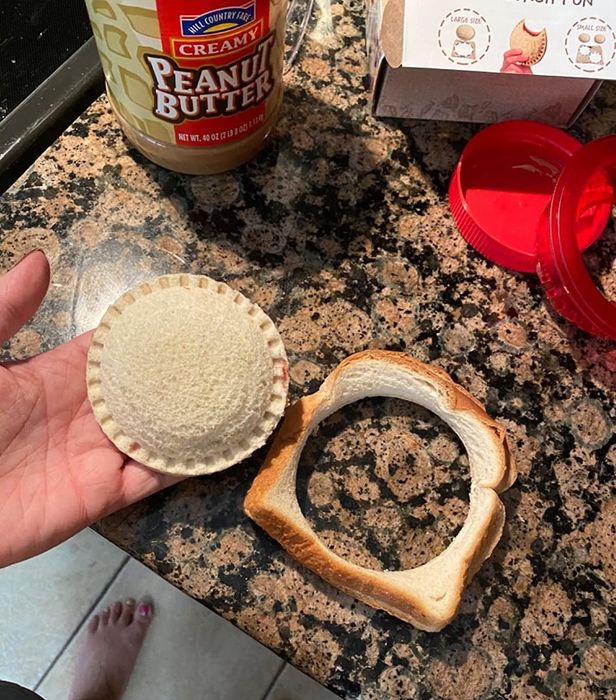 A reviewer holding a homemade circular peanut butter and jelly sandwich