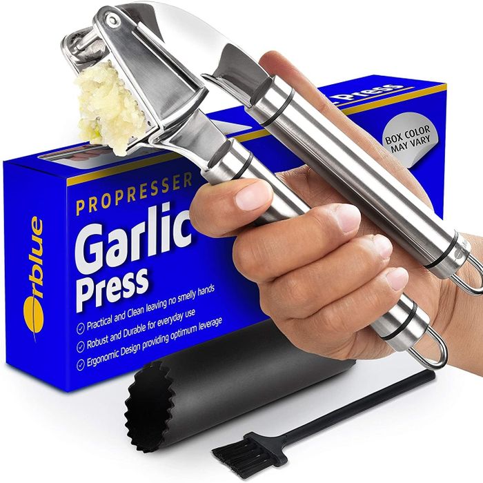 A handheld garlic press turning garlic into a thick paste