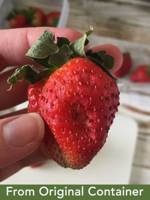 A hand holding a slightly wilted strawberry with text that reads