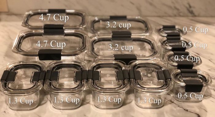 A reviewer photo of the 24-piece set laid out with storage amounts labeled, including two containers that hold 4.7 cups, two that hold 3.2 cups, four that hold 1.3 cups, and four that hold 0.5 cups