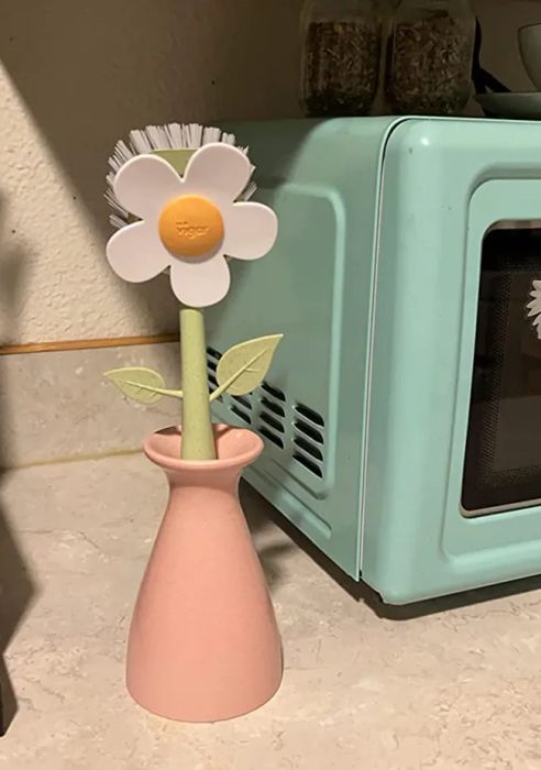 A daisy-shaped scrubber with a pink vase as its stem