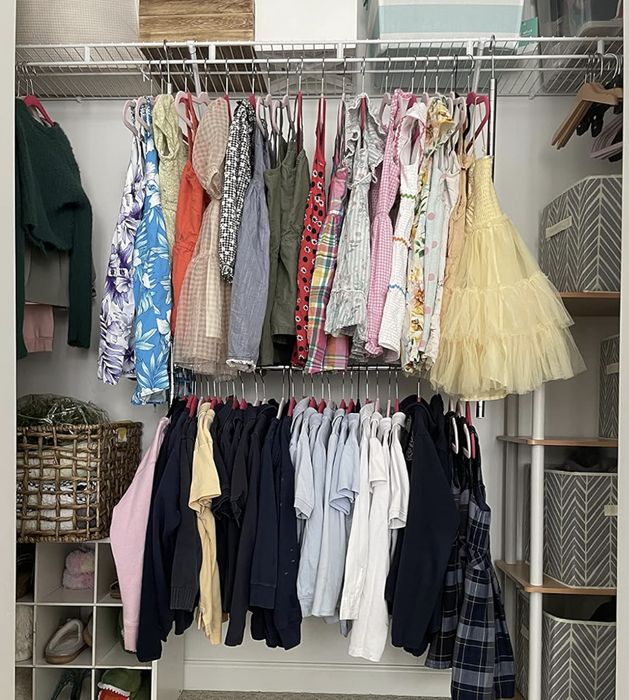 A tidy closet with colorful children's dresses hanging on the upper rod, while neatly organized shirts and pants rest on the lower rod, with storage boxes and shoes lined up on the sides