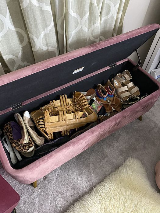 a reviewer's pink storage bench with the lid opened, revealing space for shoes inside