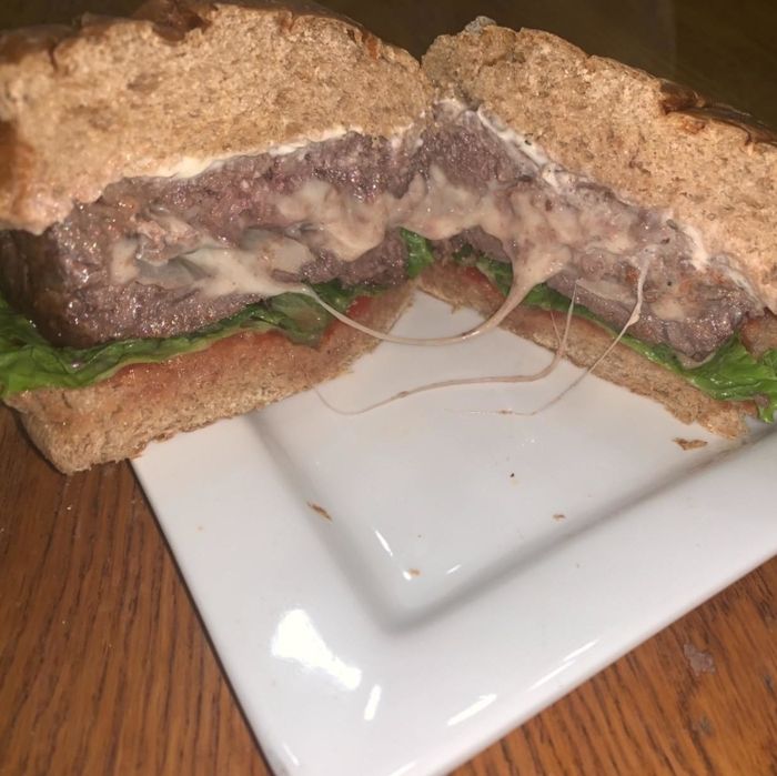 A burger sliced in half to reveal a cheesy, pepper-filled center