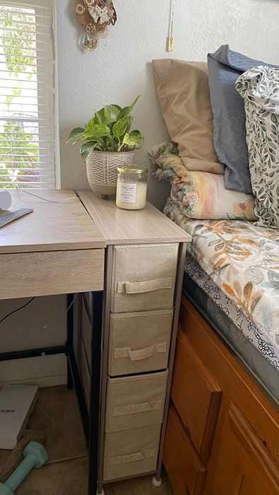 A reviewer's cream and gold organizer placed between a bed and desk, perfectly fitting the space.