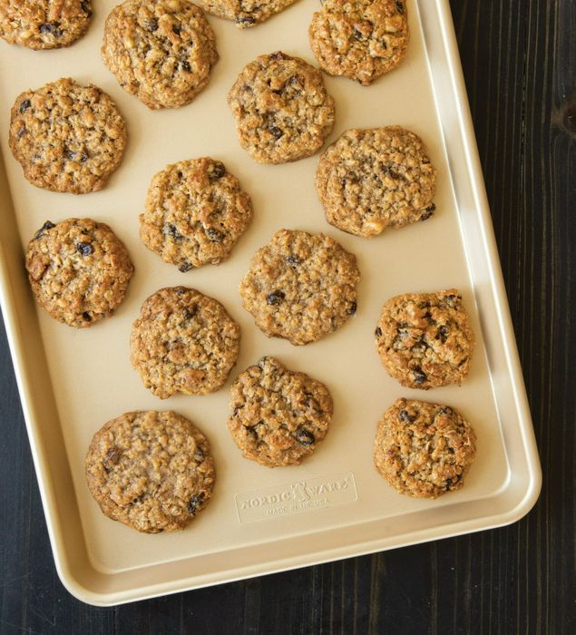 A batch of freshly baked cookies arranged on a rimmed gold baking sheet.