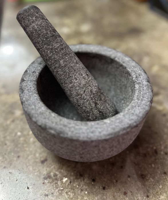 A gray granite mortar and pestle set resting on the kitchen counter, commonly used for grinding various ingredients