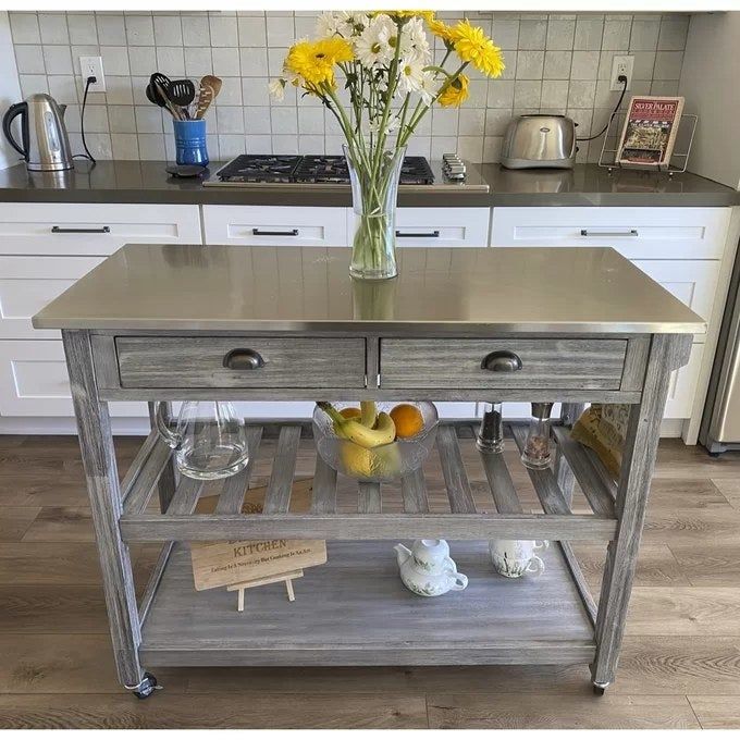 A kitchen cart with a stainless-steel surface, two drawers, and two open shelves, ready for use