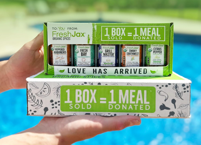 A person holding a FreshJax organic spice set, showcasing the collection.