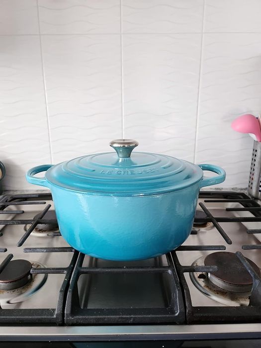 A Blue Le Creuset Dutch oven resting on a stovetop
