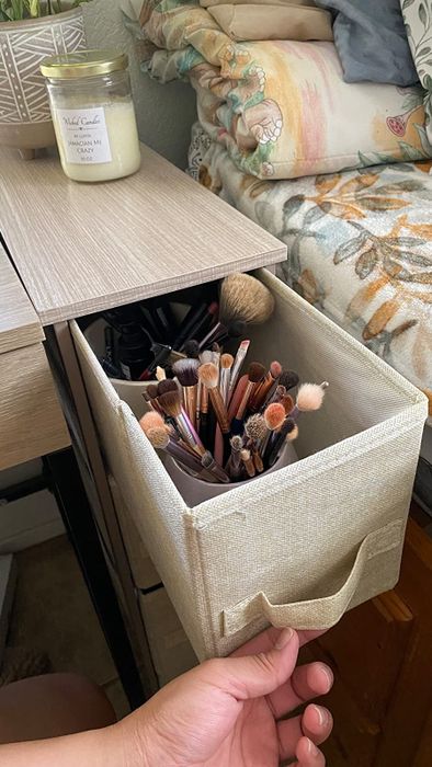 The same reviewer opening one of the drawers to showcase its depth while holding makeup supplies.