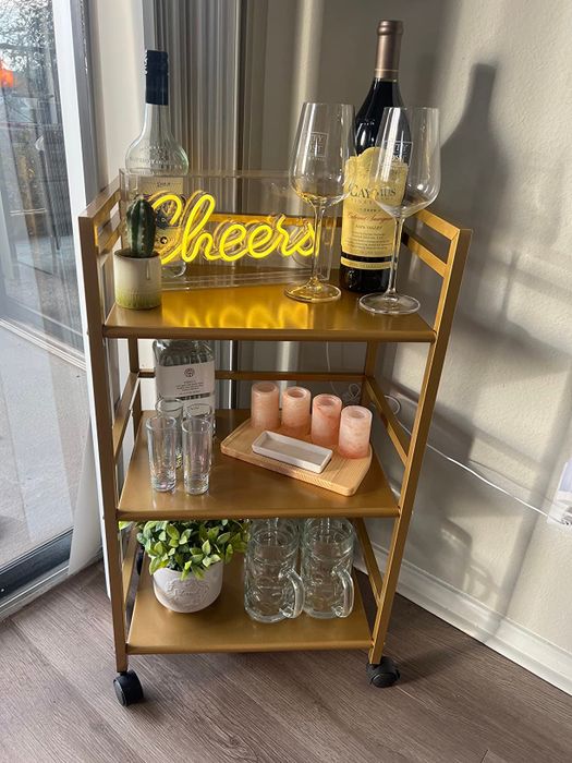 reviewer's three-tiered gold cart displaying a variety of spirits and glasses