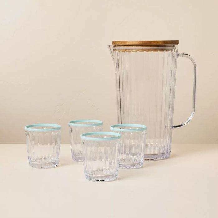 A glass pitcher with a wooden lid and four matching glasses, perfect for serving beverages on any table