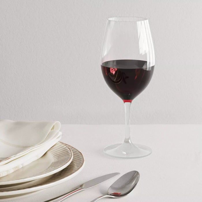 A plastic wine glass filled with red wine resting on a countertop