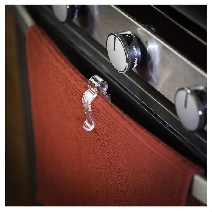 A close-up of a glass oven knob holder with a red towel hanging on it