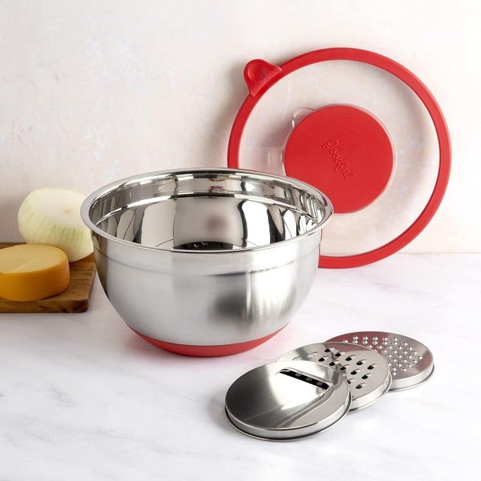 stainless steel mixing bowl featuring a red silicone lid and detachable grater tools placed on a kitchen counter