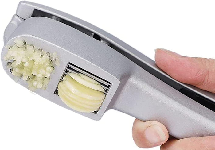 A person pressing garlic through the slicer and mincer at the same time