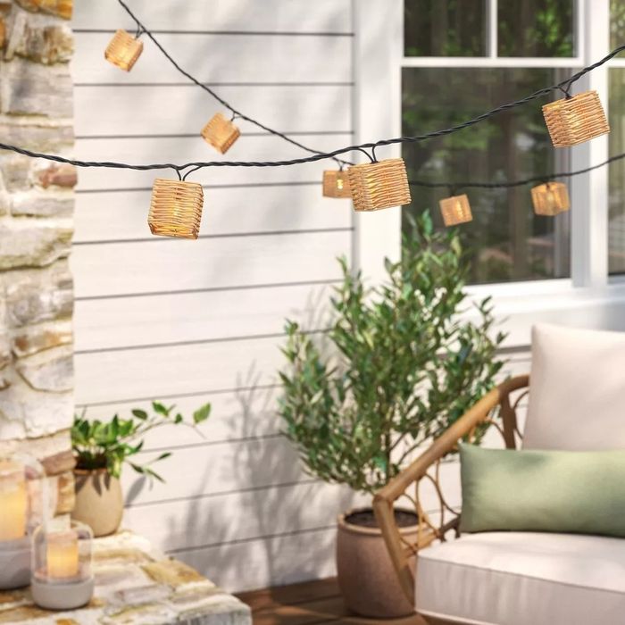 String lights with woven shades hanging above a patio, creating an inviting outdoor ambiance with furniture